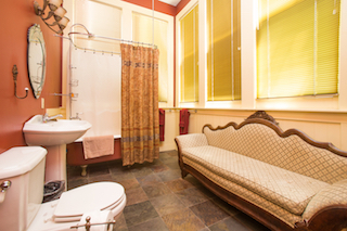 A bathroom with a sofa, shower, tub, sink, and toilet.